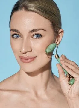 Face jade roller. Face of beautiful woman with green jade roller for anti-agi Foto stock