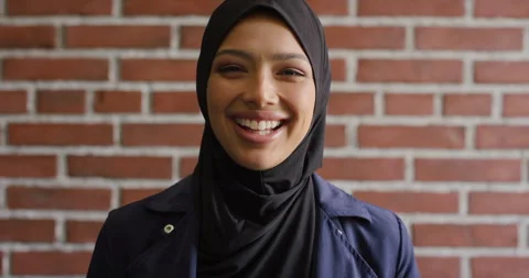 Face, laughing and learning with Muslim woman on brick wall background at Stock Footage 336644902