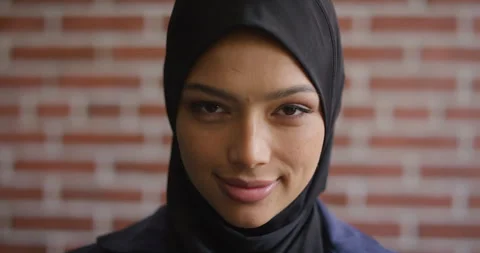 Face, learning and smile of Muslim woman on brick wall background at college Stock Footage 336645374