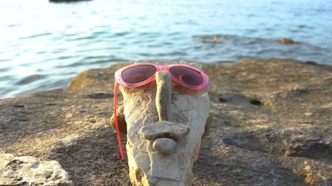 A face made from small rocks and pebbles with sunglasses and eyes Stock Footage 159062016
