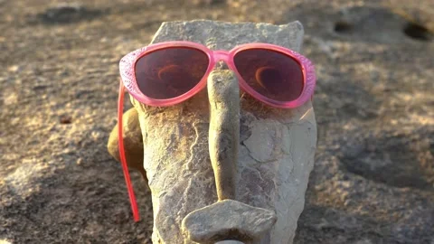 A face made from small rocks and pebbles with sunglasses and eyes Stock Footage 159062073