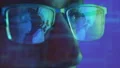 The face of a male in glasses looking on the display on the hologram background 4k or 4k+ Resolution
