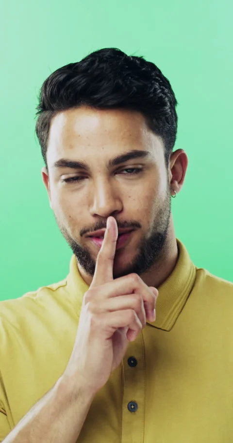 Face, man and shush in studio for secret, confidential news or hand gesture on Vídeos de archivo 334899578