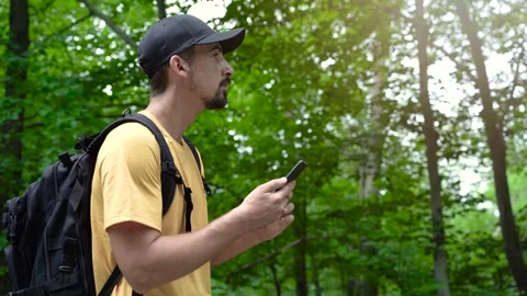 Face man with backpack in forest uses phone to touch the screen looking for Stock-Footage 277819824