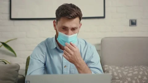 Face man remove medical protective mask laptop at home self isolation epidemic 動画素材 132540173