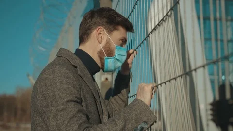 Face man wearing Protective Face Mask stand near fence border COVID-19 Stock Footage 126617029