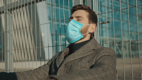 Face man wearing Protective Face Mask sitting near fence border sad close eyes Stock Footage 126617311