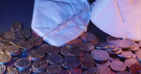 Face Mask and thermometer on top of Coins from European Union. Health Crisis Stock Footage 147943018