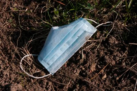 Face mask drop on ground grass floor, save the nature. garbage. in time of Foto stock