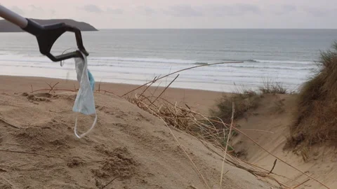 Face mask litter being picked up on Woolacombe beach in Devon, UK Stock Footage 170303624