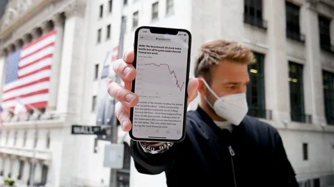Face Mask Man Looking Down Holding Out Smartphone Plummeting Stock Market Stock Footage 128704548