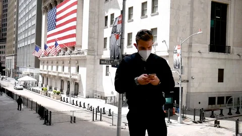 Face Mask Man Looking At Smartphone By Closed NYC Stock Exchange Wall Street Stock-Footage 128704545