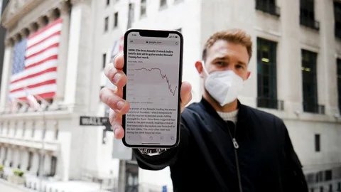 Face Mask Man Shaking Head Holds Out Smartphone Plummeting Stock Market Stock Footage 128704555