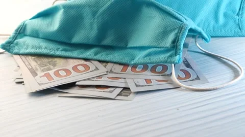 Face mask with one hundred dollar bills lies on a textured light blue surfa.. Stock Footage 333259587