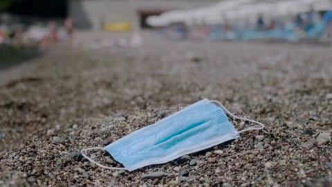 Face mask on pebble beach, with beachgoers on background. Becici, Montenegro. Stock Footage 143648469