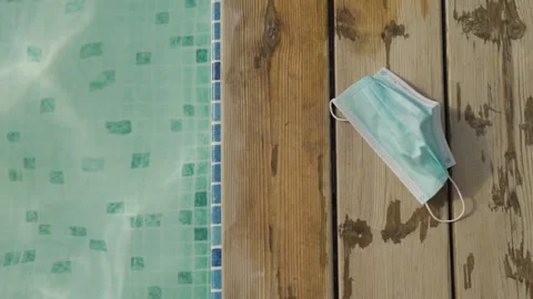 Face mask by the swimming pool during a vacation or break in covid 19 pandemic Stock Footage 140768135