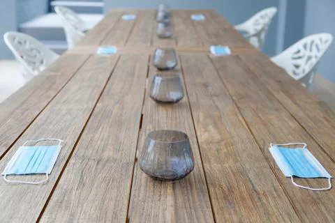 Face masks lying on a table with gaps between the chairs for social distancin Stock Photos