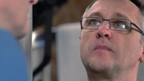 Face of middle-aged man in a mirror taking a pill Stock Footage 127932954