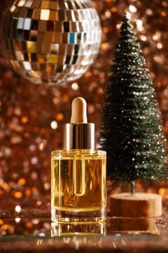 Face oil on sequin background with disco ball and tree Stock Photos
