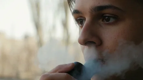 Face of pensive guy smoking electronic cigaterre outdoors. Macro of smoking Video stock 105754213