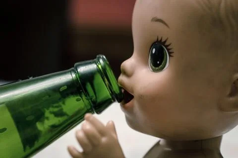 Face of a plastic doll drinking beer Stock Photos