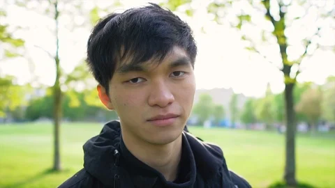Face Portrait of Confident Young 20s Asian Man in Park Stock Footage 117966460