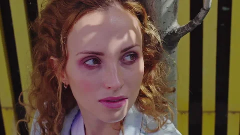 Face red curly haired young woman looking at camera against yellow wood fence. Stock Footage 160550070