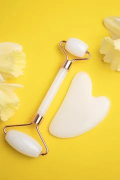 Face roller, Gua sha stone for face massage and narcissus flowers Foto stock