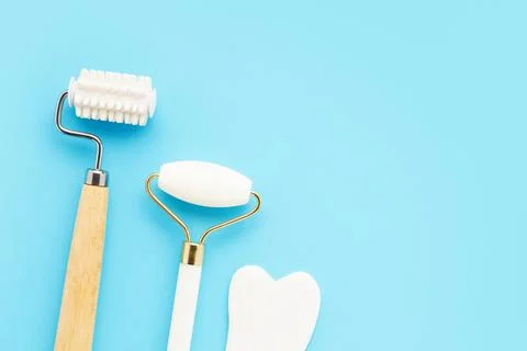 Face rollers and gua sha massager on blue background. Selfcare, skincare concept Stock Photos