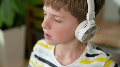 Face Of Seven Year Old Boy In Headphones. He Raises His Hand. Cute Blond Boy. Stock Footage 154324004