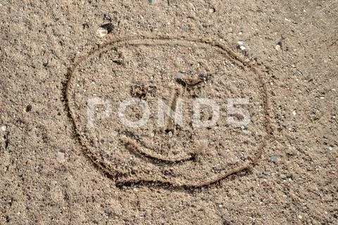 A face sketched on the sand. Children's drawing drawn with a stick on a woode Stock Photos