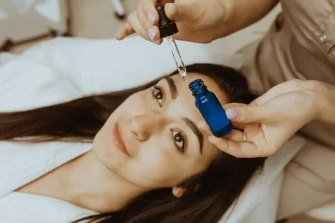 Face skin care. Close up of beautiful smiling woman receiving serum oil Stock Photos