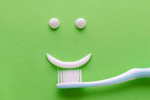A face with smile from white toothpaste, teeth care concept, toothbrush on green Stock Photos