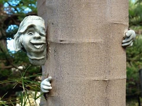 A face of stone on a tree trunk, one hand on the right Stock Photos