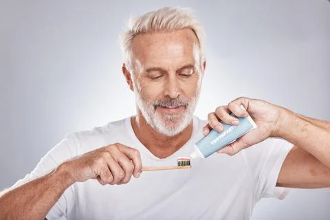 Face, toothpaste and senior man with toothbrush in studio isolated on a gray Stock Photos
