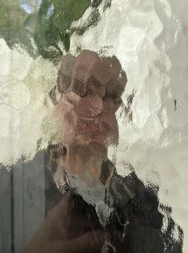 Face in wavy pattern glass window with blurred and distorted face concept  Stock Photos