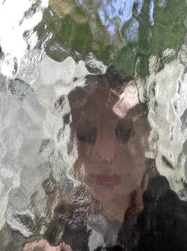 Face in wavy pattern glass window with blurred and distorted face concept for me Stock Photos