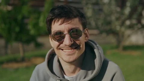 Face of a young attractive guy in sunglasses looking at the camera smiling Stock Footage 247913851
