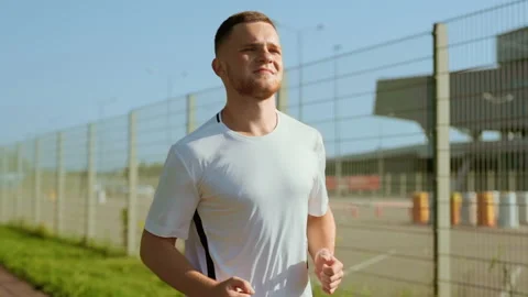 Face young attractive man running on street look around at sunlight. Runner Stock Footage 140365943