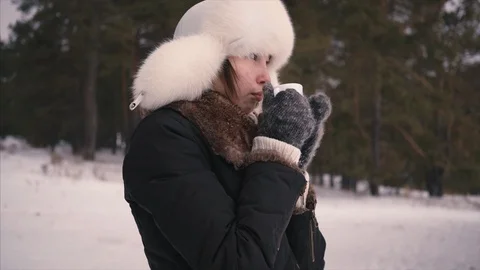 Face of young girl drinking hot coffee outdoors in winter forest 스톡 동영상 101855243