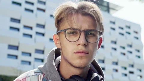 Face Of Young Handsome Guy. Serious Look. He Is On The Street With Headphones Stock Footage 143344768