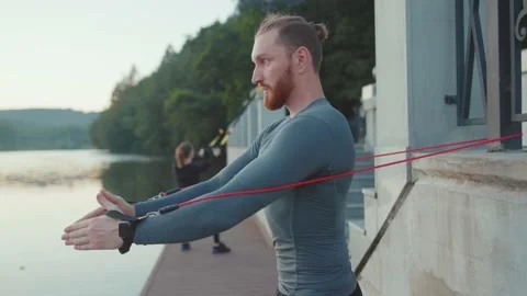 Face young man exercising with trx suspension strap near lake crossfit healthy Stock Footage 138652709