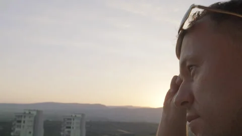 The face of a young man who puts on sunglasses and looks at the city Stock Footage 303632728