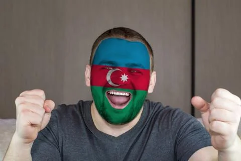 Face of young screaming  man painted with flag of Azerbaijan.  Soccer team fan. Illustrazione stock