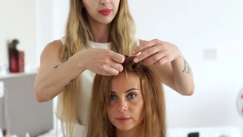 Face young woman while creating hairstyle in beauty studio. Hairdresser making Video stock 91881875