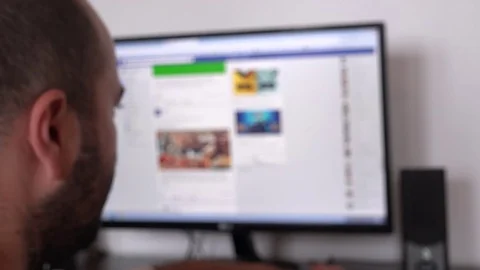 Facebook news feed in blur on Desktop computer monitor man face closeup checking Stock Footage