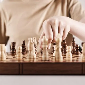 Faceless boy develops game strategy. Hand holds chess piece and makes a move Stock Photos