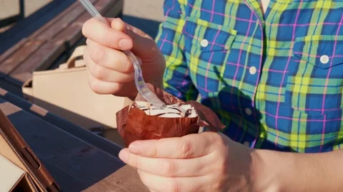Faceless girl with fork eats sweet muffin outdoors. Stock Footage 134474448