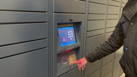 Faceless man dialing a code in Amazon hub with lockers. Parcel station for Stock Footage 271317934