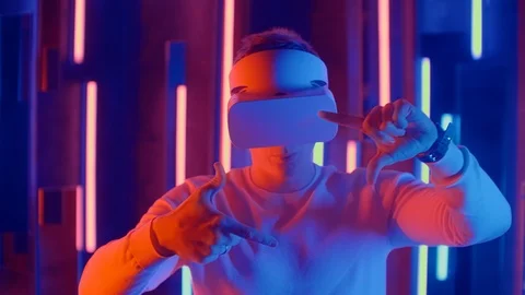 Faceless man wearing VR headset in dark space with neon light lamps, user Stock Footage 123868555
